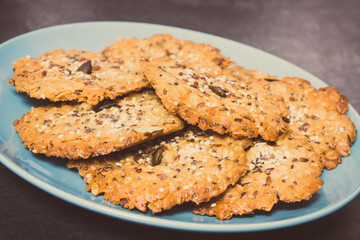 Fresh baked oatmeal cookies with honey and healthy seeds on blue glass plate. Delicious crunchy dessert
