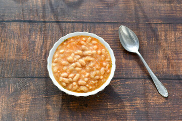  Homemade bean soup .Steamed white beans in tomato sauce  on a wooden background  