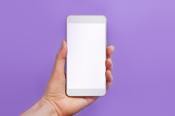 Mockup of a mobile phone with a white screen on a lilac background. Veri Peri Color of the Year 2022. female hand holding mobile phone isolated on purple background