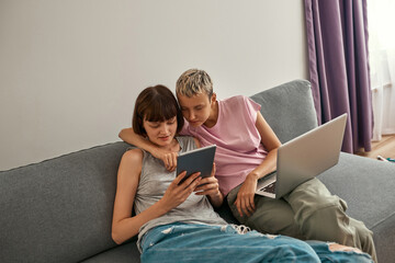 Fototapeta na wymiar Young lesbians watching on digital tablet on sofa