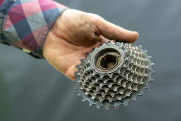 Repair of mountain and road bikes. Mechanic's hands and a cassette close-up on a black background. Replacement of worn-out spare parts.
