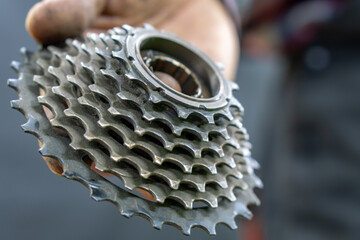 Repair of mountain and road bikes. Mechanic's hands and a cassette close-up on a black background. Replacement of worn-out spare parts.