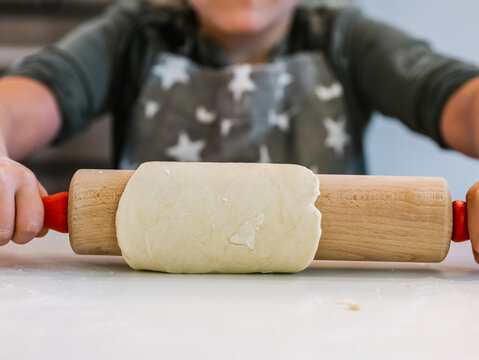 Anonymous girl kneading dough with rolling pin