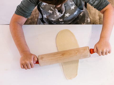 Anonymous girl kneading dough with rolling pin