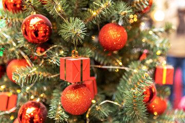Fototapeta na wymiar Christmas tree decorated with red ball and gift boxes. Background with bokeh. New Year