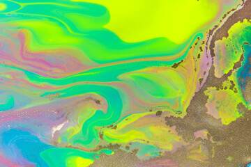 Yellow gold dust scattered on vivid ink colorful background.