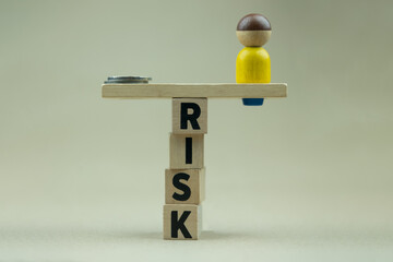 Money between wooden human figures placed on balancing wooden cubes with text Risk like a pole