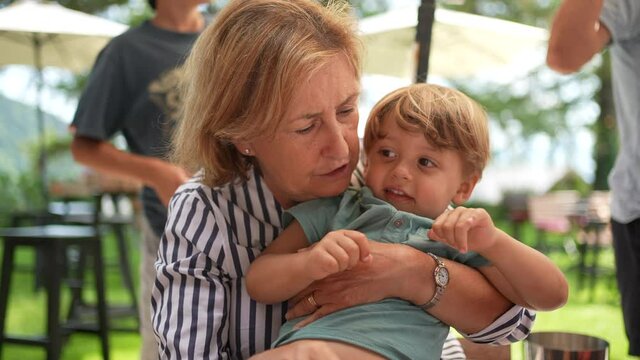 Grand-mother holding toddler grand-son in arms outside. candid and real life
