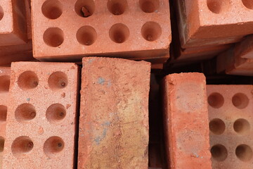 A pile of building materials, stack of new red bricks for construction are accurately put together.