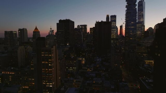 Elevated ascending footage of tall office or apartment buildings in city, silhouettes of skyscrapers against twilight sky. Manhattan, New York City, USA