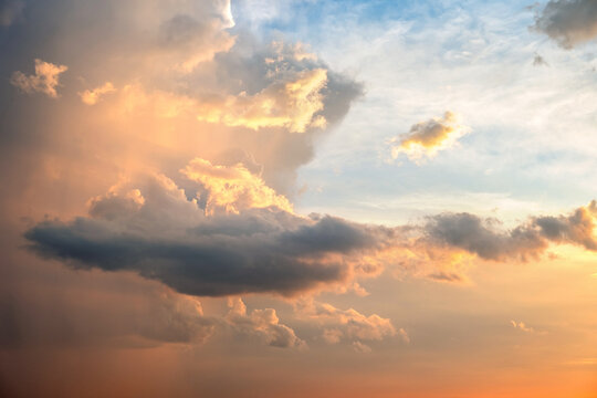 Dramatic sky at sunset with puffy clouds lit by orange setting sun © bilanol