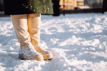 Cropped image of women's winter white shoes in the snow. Warm comfortable waterproof boots. Footwear for winter. Copyspace.