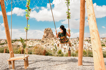 Dreamy caucasian girl on famous Cappadocia swings enjoy sunny day in Ortahisar, Turkey