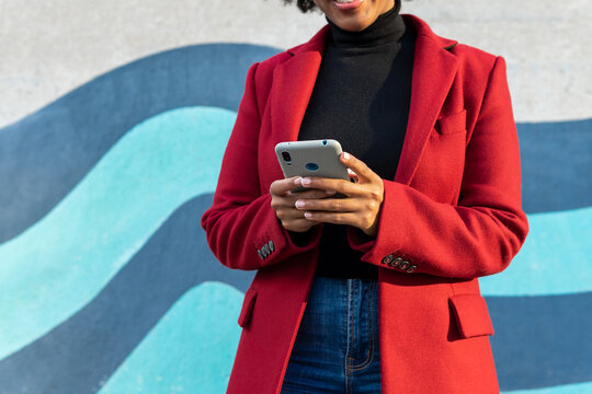 Anonymous African American woman in formal jacket with smartphone