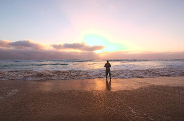 Naklejka premium pescador en la orilla de la playa del mar en el ocaso