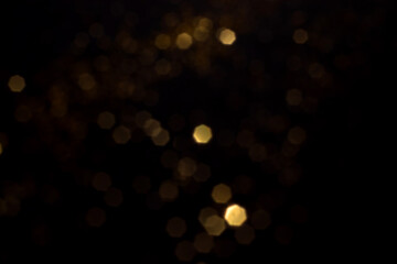 Golden blurred bokeh lights on black background. Glitter sparkle stars for celebrate. Overlay for...