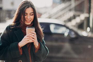 Young woman drinking coffee by her car