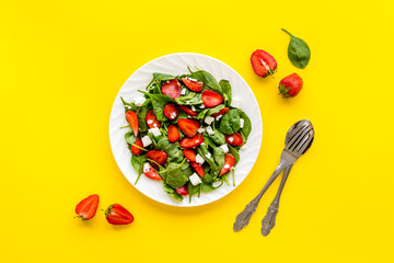 Top view of spinach salad with strawberry and goat cheese
