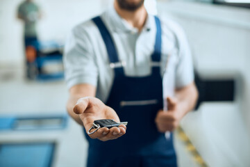 Close-up of mechanic holds car keys in auto repair workshop.