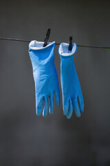 Blue rubber household gloves hanging on a clothesline outside