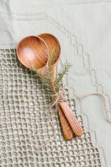 Fototapeta na wymiar Two wooden spoons on green tablecloth. Spoons for soup, salad or porridge. Eco friendly kitchen utensils. Christmas or winter table setting