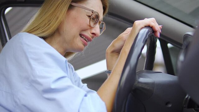 Upset frustrated blond woman crying sitting on driver seat in car, suffering break-up or divorce, catching her boyfriend on cheating, releasing her bad emotions to relax, emotional burnout, stress