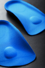 Orthopedic insoles for correction of the blue color of the foot on a black background.