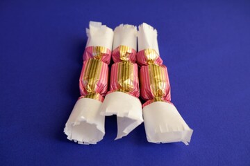 traditional Hungarian Christmas sweets named szaloncukor in bright vibrant pink and golden colour packaging on violet colour background