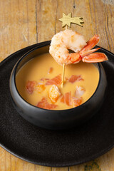 Top view of black bowl with prawns and salmon cream, on rustic table, in vertical