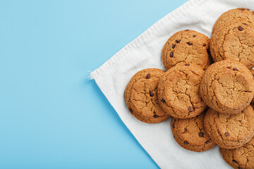 A bunch of oatmeal cookies with chocolate on a napkin on a blue background