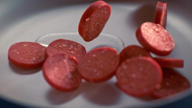 Sliced Turkish sausages (sucuk) fall into the pan in slow motion. Sliced sausage being thrown into a pan in slow motion. Macro, 4K, Phantom Camera,Super Close-Up. Slow motion. 