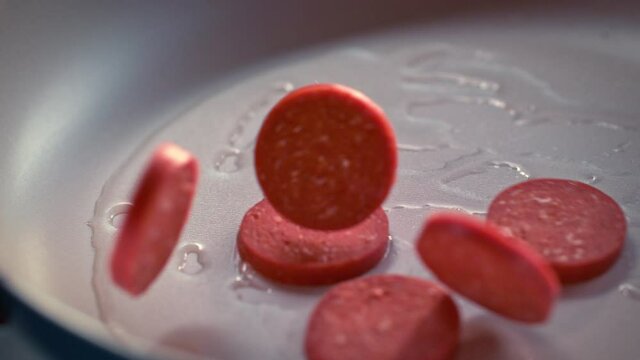 Sliced Turkish sausages (sucuk) fall into the pan in slow motion. Sliced sausage being thrown into a pan in slow motion. Macro, 4K, Phantom Camera,Super Close-Up. Slow motion. 