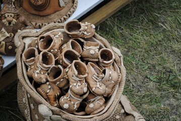 Clay shoes in bulk in a basket made by craftsmen for decoration. Fair goods