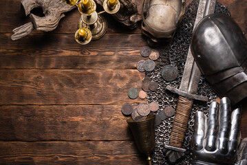 Knight sword, helmet and armor on the wooden flat lay table background with copy space.