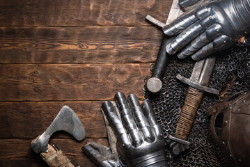 Knight sword, helmet and armor on the wooden flat lay table background with copy space.