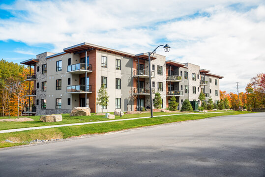 Brand new apartment building surrounded by colourful trees in a housing development on a partly clody autumn morning