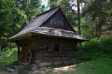 Small wooden blacksmith hut in woods of Orava region of northern Slovakia, some wheel visible in front of the doors. Location Vychylovka outdoor museum, Orava, northern Slovakia.