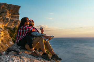 A stylish couple admires the seascape at sunset. A couple in love at sunset by the sea. A man and a...