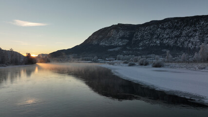 Sunrise over the river Hallingdalselva. Shot at Nesbyen, Norway. It is December and minus 20 degree outside. The water in the river is warmer than the air so therefor the smoke on the river. Frost. 