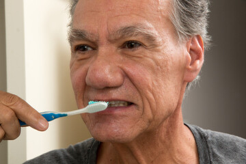 Mature Man Brushing his teeth with a Worn out Tooth Brush