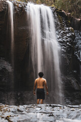 Obraz premium Cascada con hombre de espaldas