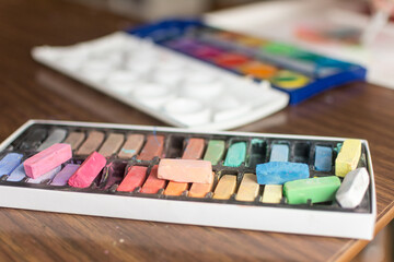 Chalk pastels and water color paints laid out in front of a high chair for child to make art with