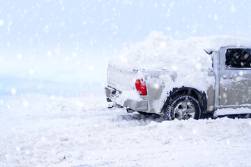 Winter snowstorm background with snow-covered pickup truck. © Dmytro