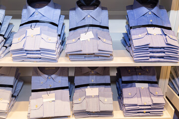 A pile of bluish shirts on a shelf