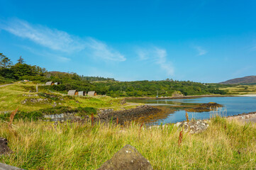 Isle of Eigg, Small Isles, Hebrides, Scotland.  A beautiful bay at low tide surrounded by woodland and silver sands. Clear blue sky. Horizontal, space for copy