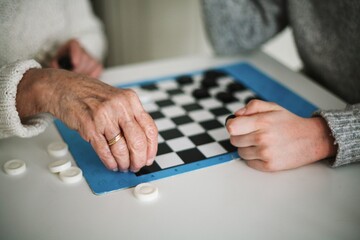 Fototapeta Family time - grandmother playing checkers with her grandson obraz