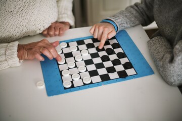 Family time - grandmother playing checkers with her grandson - obrazy, fototapety, plakaty