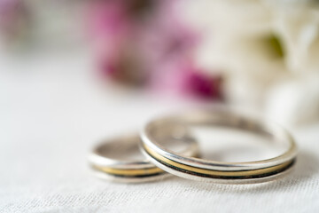 Extremely close-up of a pair of wedding or engagement rings with an out of focus background of beautiful violet flowers.