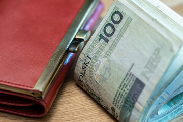 thick bundle of folded 100 zloty banknotes from Poland, table, wallet, close-up