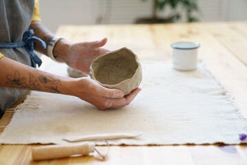 Cropped image of female potter sculpting clay pot with hands. Ceramist woman work with raw earthenware creating handmade pottery. Workplace of ceramics master. Craftsmanship and small business concept